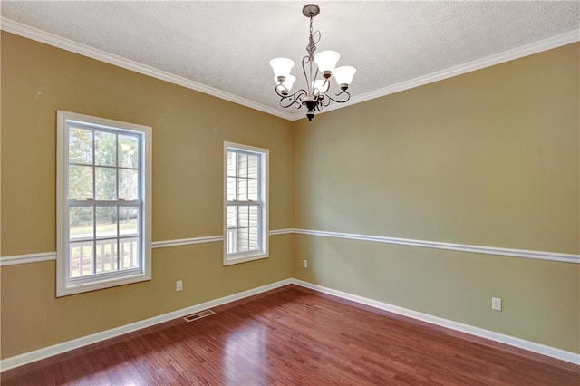 spare room featuring hardwood / wood-style floors, ornamental molding, a textured ceiling, and a notable chandelier