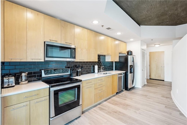 kitchen with sink, stainless steel appliances, light brown cabinetry, and light hardwood / wood-style flooring