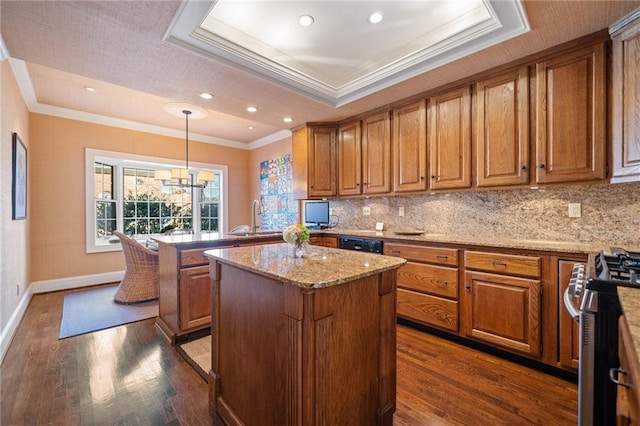 kitchen with stainless steel range with gas stovetop, decorative light fixtures, a raised ceiling, and a kitchen island