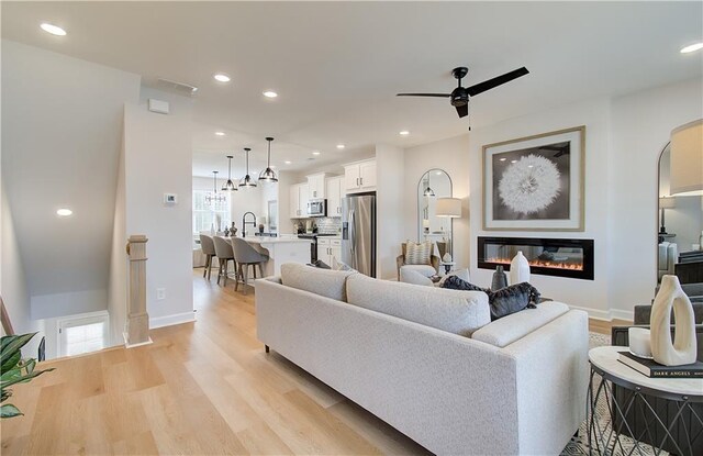 living room with ceiling fan, sink, and light hardwood / wood-style floors