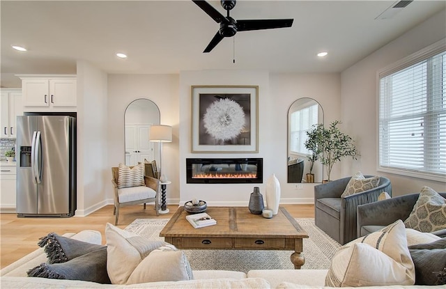 living room with ceiling fan, plenty of natural light, and light hardwood / wood-style floors