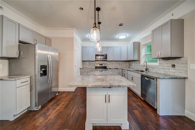 kitchen featuring stainless steel appliances, dark wood-type flooring, sink, decorative light fixtures, and a center island