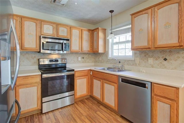 kitchen featuring visible vents, a sink, tasteful backsplash, stainless steel appliances, and light wood finished floors