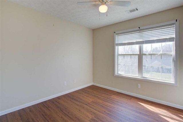 spare room with a ceiling fan, wood finished floors, baseboards, visible vents, and a textured ceiling