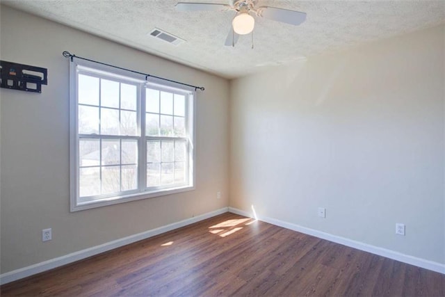 spare room featuring visible vents, baseboards, a textured ceiling, and dark wood finished floors