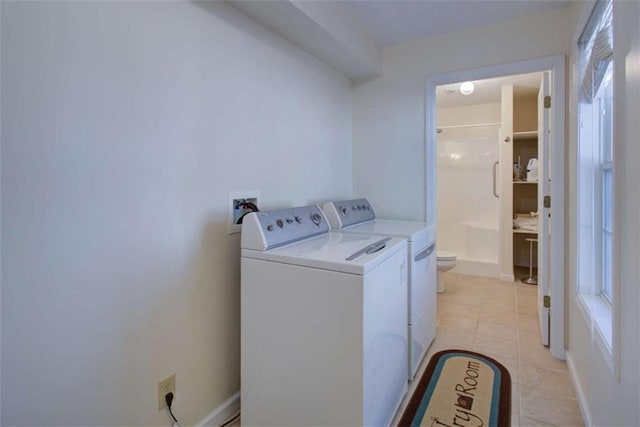 laundry area featuring light tile patterned floors, baseboards, separate washer and dryer, and laundry area