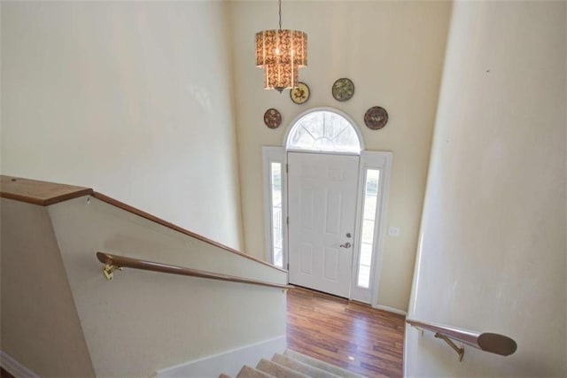 entryway featuring stairway, a notable chandelier, wood finished floors, and baseboards