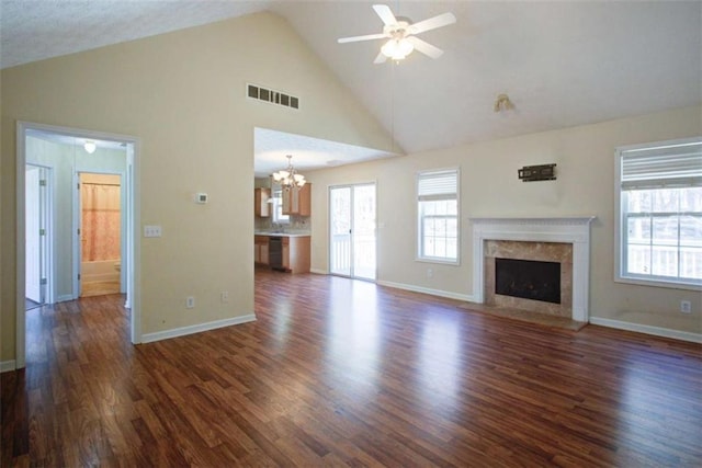 unfurnished living room featuring visible vents, ceiling fan with notable chandelier, a fireplace, dark wood-style floors, and high vaulted ceiling