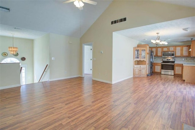 unfurnished living room with ceiling fan with notable chandelier, baseboards, visible vents, and light wood-type flooring