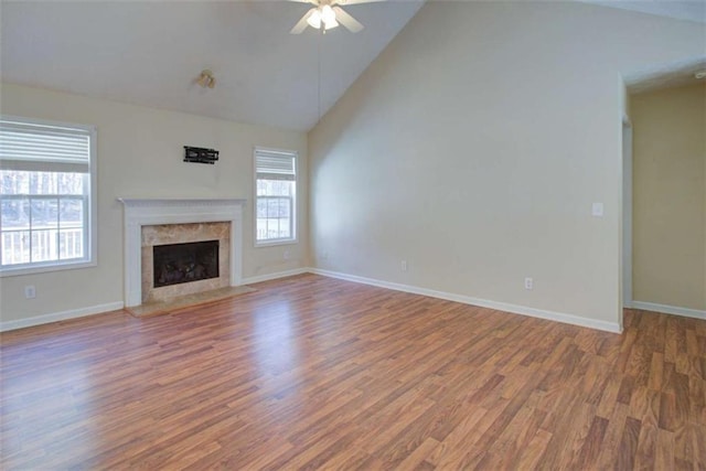 unfurnished living room with a premium fireplace, baseboards, and wood finished floors