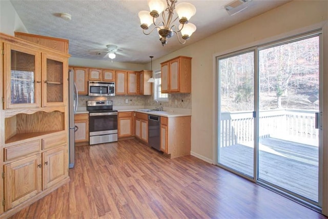 kitchen featuring backsplash, light countertops, light wood-style floors, stainless steel appliances, and a sink