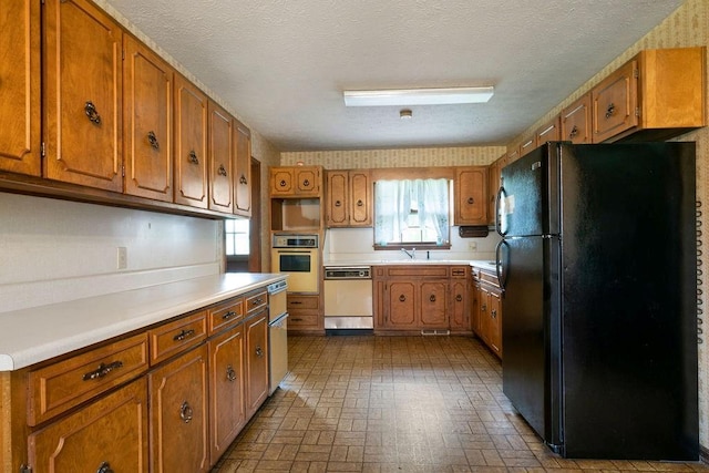 101 Beaver Run, Lagrange, GA 30241 - kitchen featuring freestanding refrigerator, dishwasher, oven, brown cabinets, and a textured ceiling