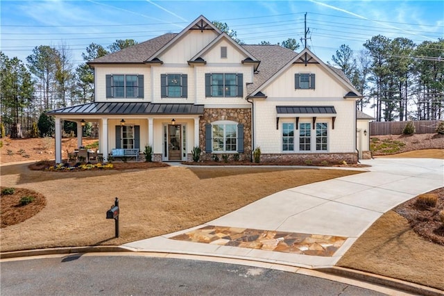 view of front of property with a shingled roof, fence, a porch, stone siding, and a standing seam roof