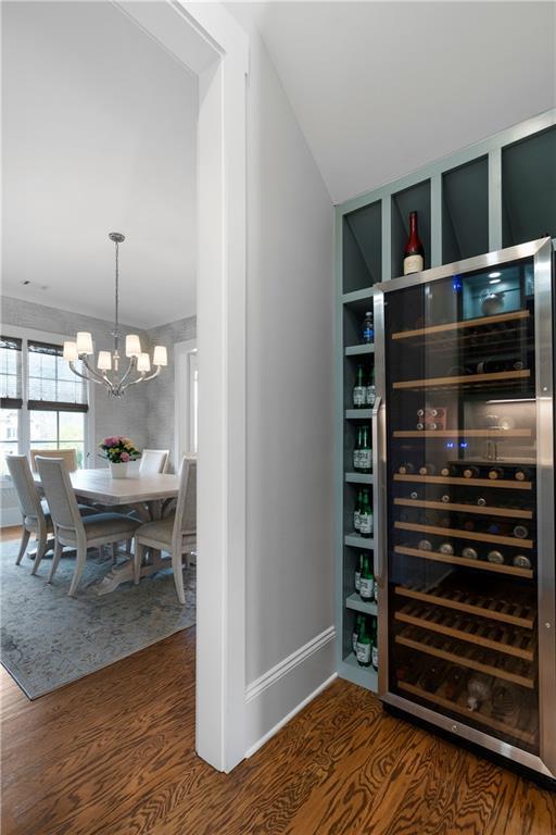 interior space with beverage cooler, a notable chandelier, lofted ceiling, and wood finished floors