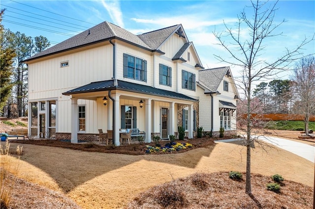 modern farmhouse featuring a standing seam roof, a porch, board and batten siding, and metal roof