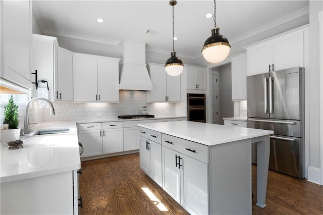 kitchen featuring a sink, premium range hood, crown molding, and freestanding refrigerator