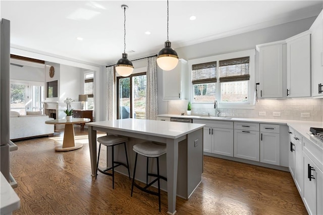 kitchen featuring dark wood finished floors, a kitchen breakfast bar, tasteful backsplash, and a sink