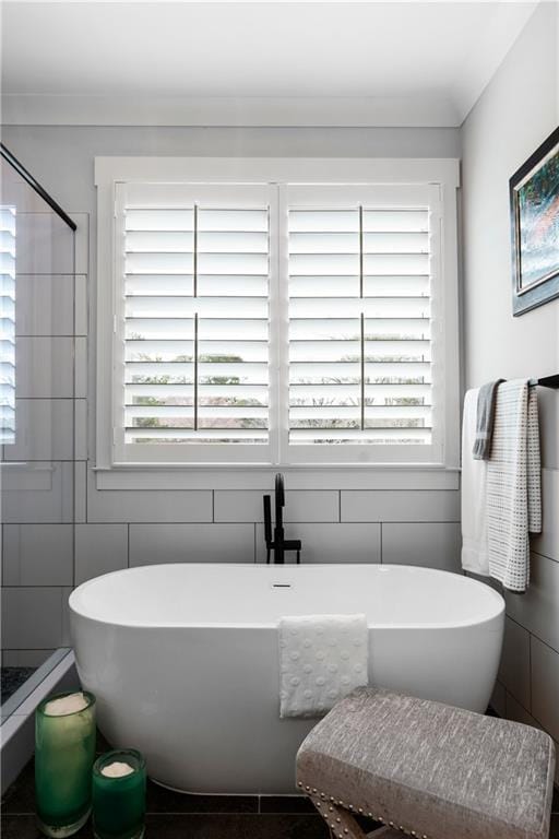 bathroom featuring tile walls, a soaking tub, and a stall shower