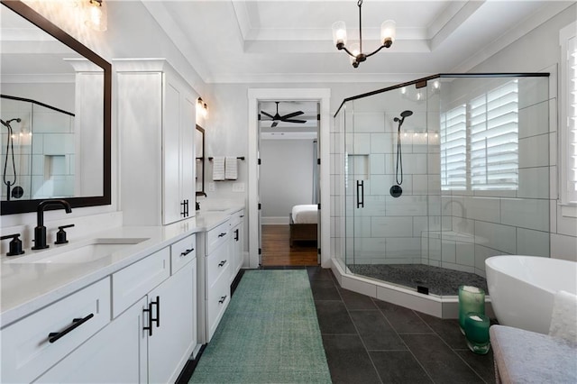 bathroom featuring a tray ceiling, ceiling fan with notable chandelier, and a shower stall