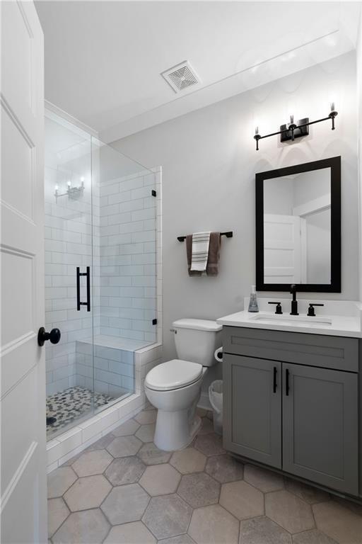 full bathroom with vanity, toilet, visible vents, and a stall shower