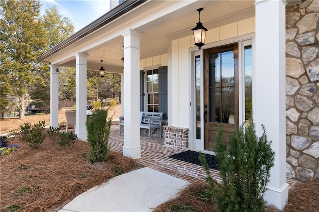 entrance to property featuring stone siding, covered porch, and board and batten siding