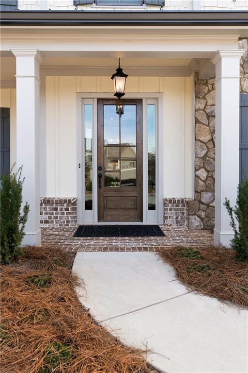 doorway to property with stone siding, roof mounted solar panels, and covered porch