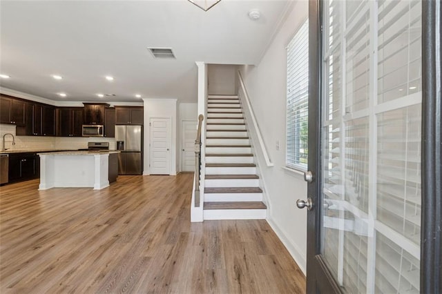 6761 Cedar Glen Rd, Peachtree Corners, GA 30360 - kitchen with stainless steel appliances, tasteful backsplash, light countertops, dark brown cabinetry, and light wood-type flooring