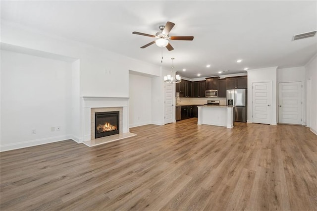 6761 Cedar Glen Rd, Peachtree Corners, GA 30360 - unfurnished living room featuring ceiling fan, recessed lighting, a tiled fireplace, light wood-style flooring, and a chandelier