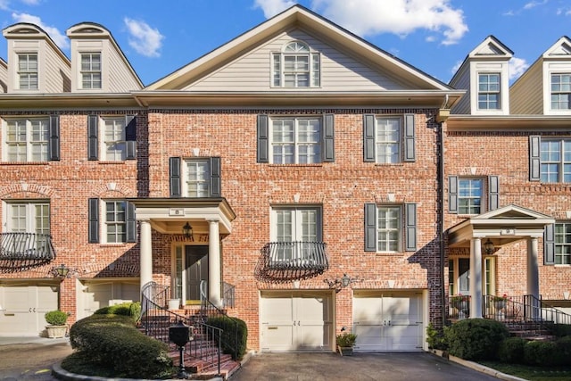 view of property featuring a garage, brick siding, and driveway