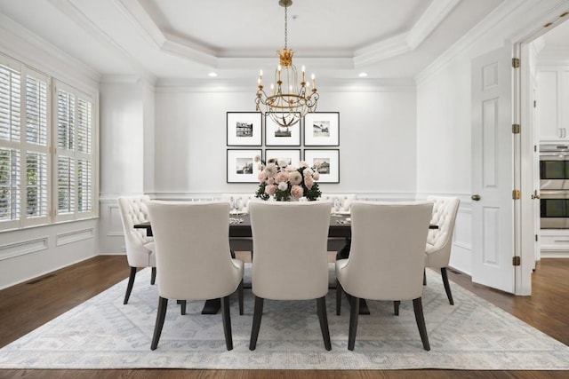 dining room with ornamental molding, a raised ceiling, hardwood / wood-style floors, and a notable chandelier