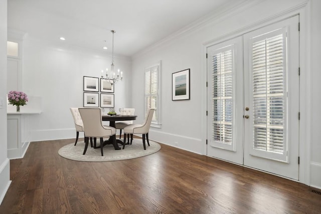 dining area with ornamental molding, dark hardwood / wood-style flooring, an inviting chandelier, and french doors