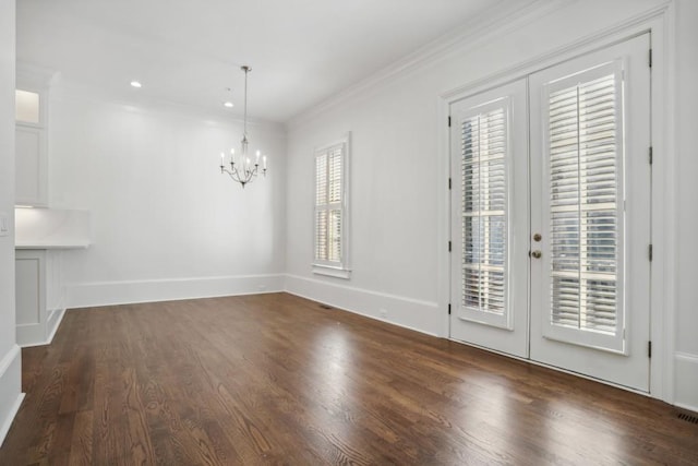 unfurnished dining area with an inviting chandelier, crown molding, dark hardwood / wood-style floors, and french doors