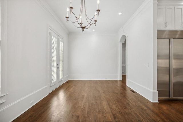 unfurnished dining area featuring dark wood-type flooring, ornamental molding, and a chandelier