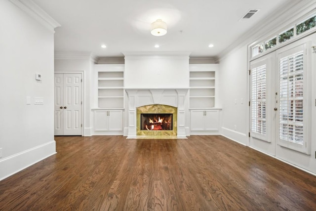 unfurnished living room with crown molding, a fireplace, dark hardwood / wood-style floors, and built in shelves