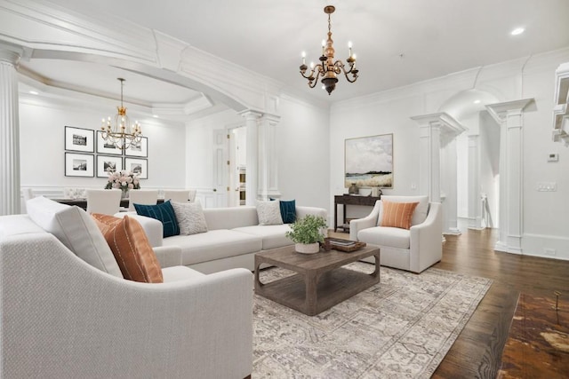 living room with a notable chandelier, ornamental molding, and decorative columns