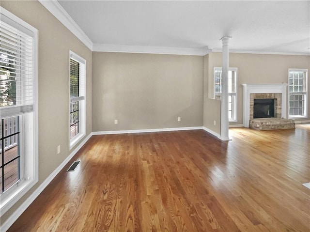 unfurnished living room featuring hardwood / wood-style flooring, crown molding, decorative columns, and a fireplace