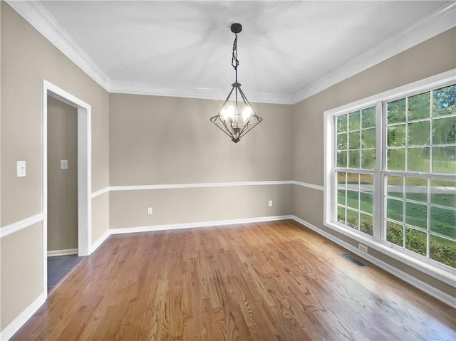 spare room featuring hardwood / wood-style flooring, crown molding, and a notable chandelier