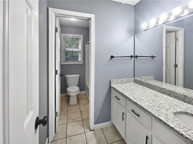 bathroom featuring a tub, vanity, tile patterned flooring, and toilet