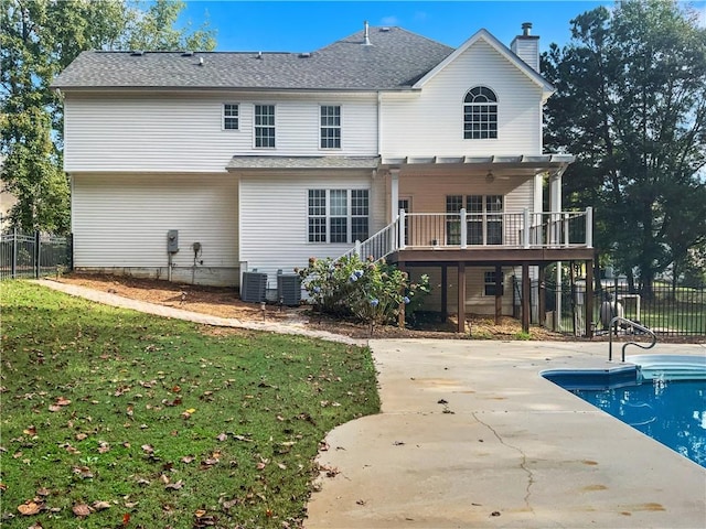 rear view of property featuring cooling unit, a lawn, a patio area, and a swimming pool side deck