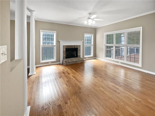 unfurnished living room featuring wood-type flooring, decorative columns, a wealth of natural light, and ceiling fan