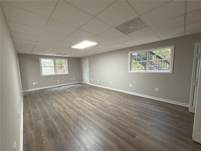 spare room with a wealth of natural light, a paneled ceiling, and dark hardwood / wood-style floors