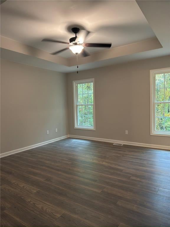 spare room featuring dark wood-type flooring, ceiling fan, and a tray ceiling