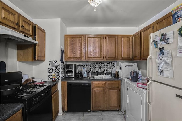 kitchen with light tile patterned floors, washer / dryer, sink, and black appliances