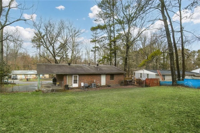 rear view of house featuring central AC unit and a yard