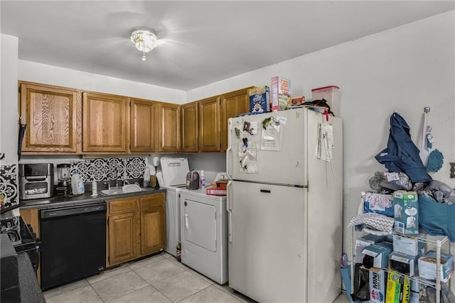 kitchen featuring sink, light tile patterned floors, black appliances, and washer and dryer