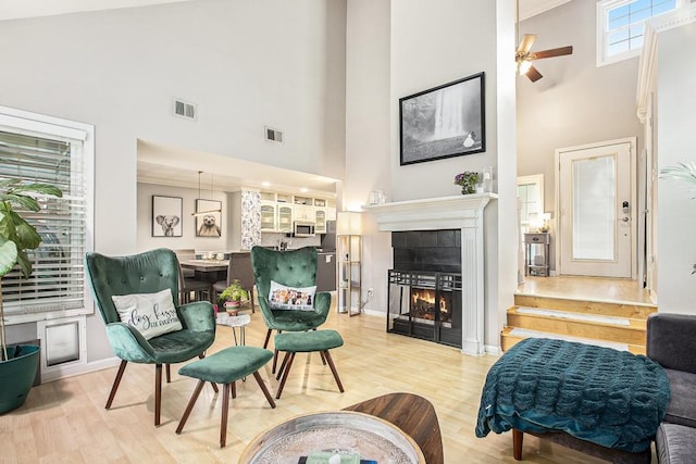 114 Emily Ln, Alpharetta, GA 30009 - living area featuring a high ceiling, light wood-type flooring, a tiled fireplace, baseboards, and a ceiling fan