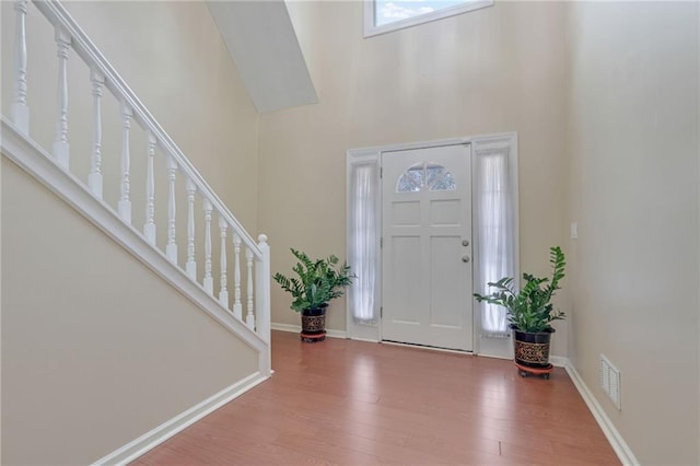 entrance foyer with a towering ceiling and wood-type flooring