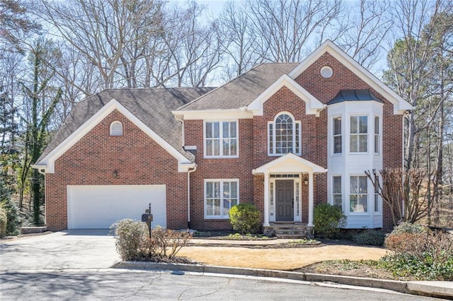 colonial inspired home with driveway, brick siding, and an attached garage