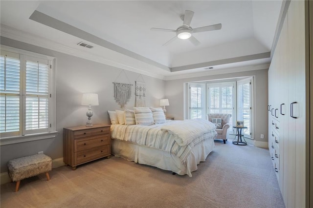 bedroom featuring light carpet, multiple windows, a raised ceiling, and visible vents