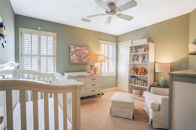 bedroom with a closet, light colored carpet, visible vents, a crib, and baseboards